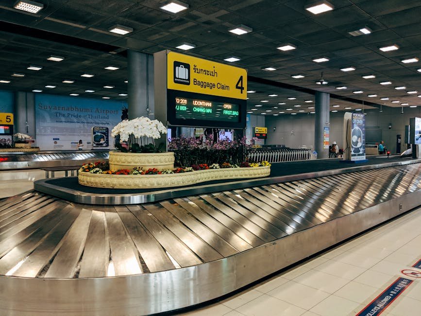 Modern baggage claim area at Suvarnabhumi Airport in Bangkok with luggage carousel and signage.