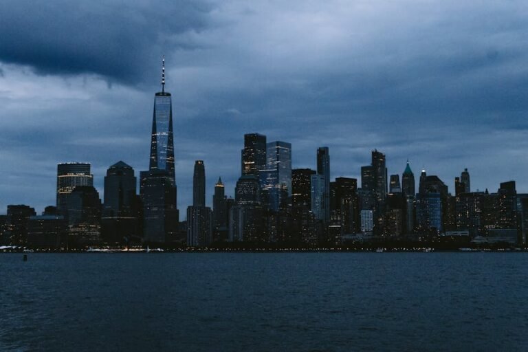 A striking view of New York City's skyline featuring One World Trade Center under an overcast sky at dusk.