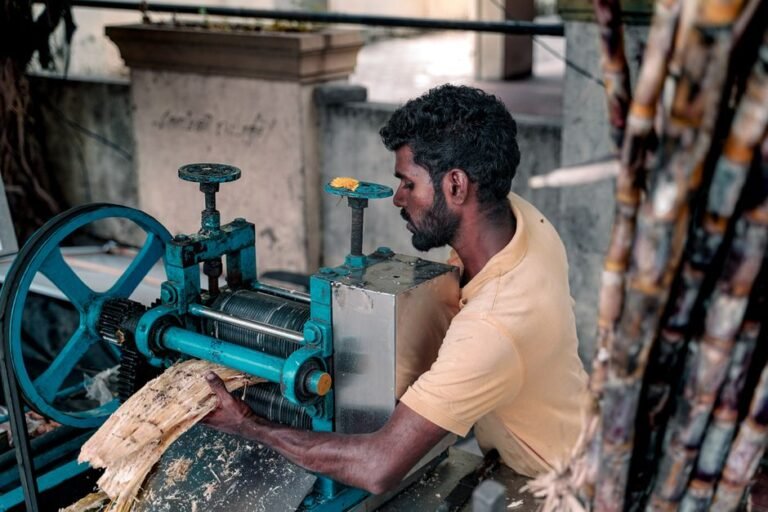 South Asian man using traditional machine to extract fresh sugarcane juice in Chennai.