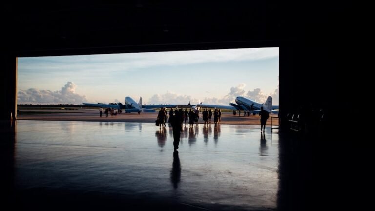 Silhouettes of unrecognizable travelers walking towards big aircrafts located on airstrip of airport