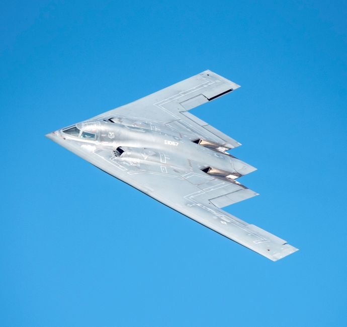 A high-resolution image of a B-2 stealth bomber flying against a clear blue sky.