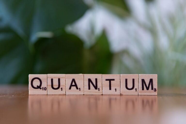 Creative depiction of 'quantum' using wooden letter blocks on a blurred natural background.