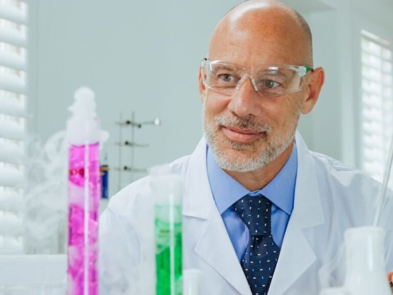 Scientist in protective gear conducting chemical experiments in a laboratory setting.
