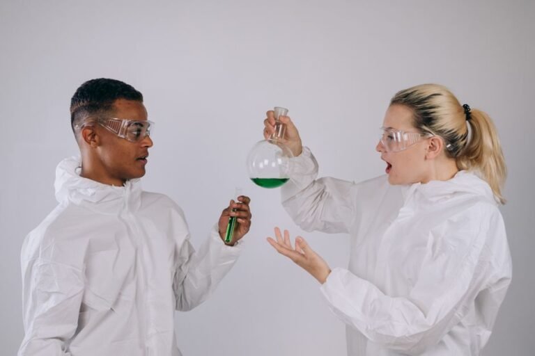 Two scientists in protective gear conducting an experiment with green liquid in laboratory setting.