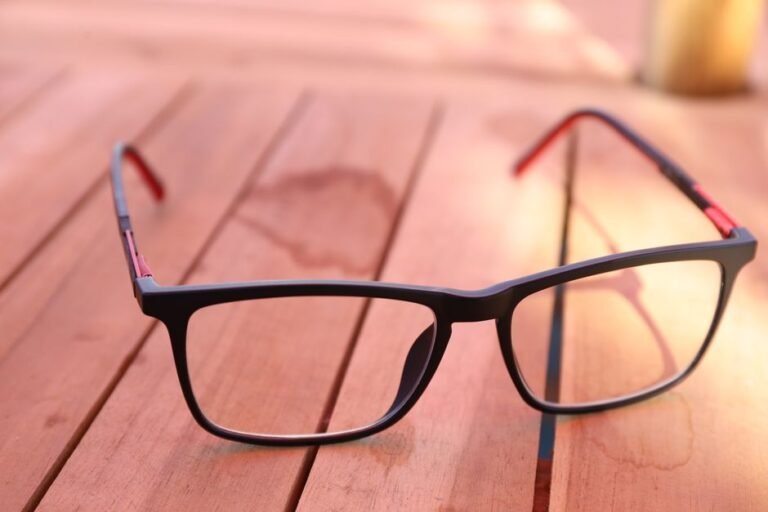 Close-up of stylish black eyeglasses on a wooden table with warm lighting.