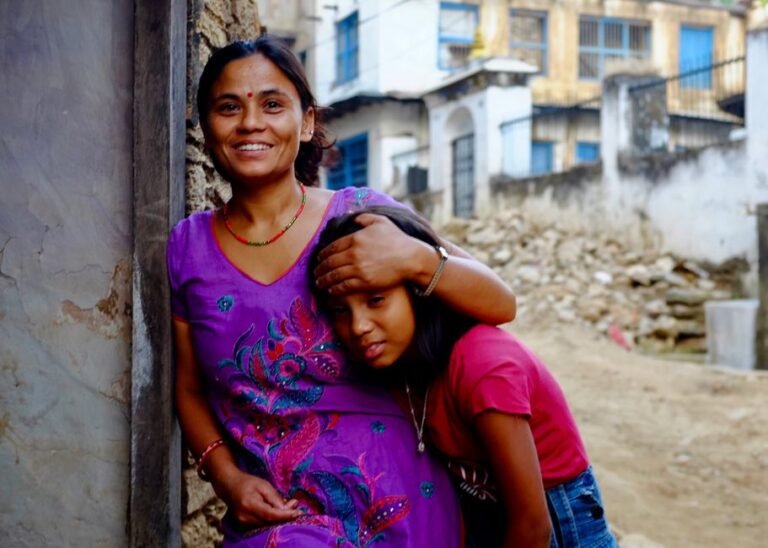 A cheerful mother and daughter share a moment in an outdoor urban environment.