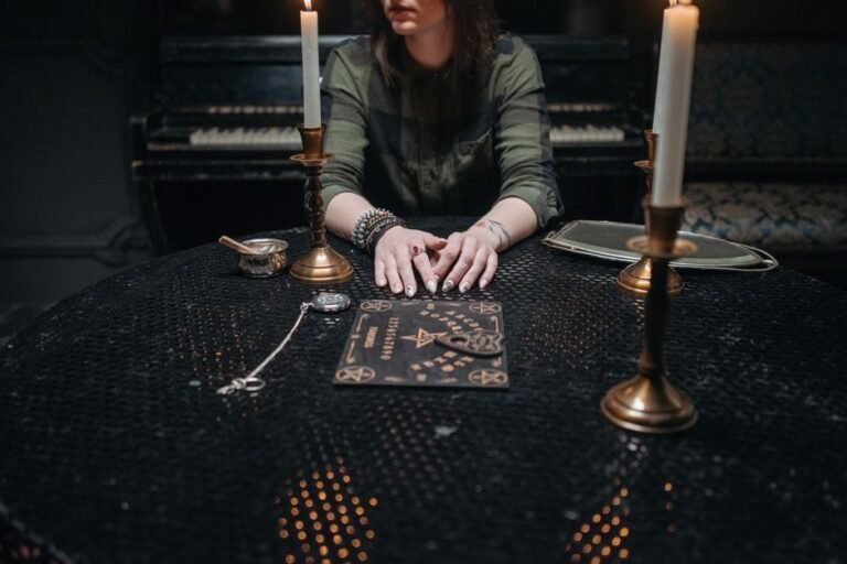 Woman sitting at a table with candles and a Ouija board, ambient setting.