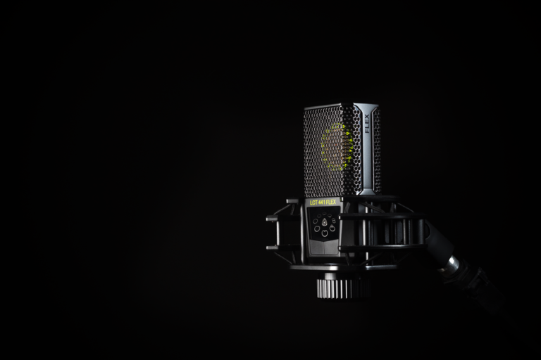 A detailed studio shot of a condenser microphone against a black background, emphasizing modern audio technology.