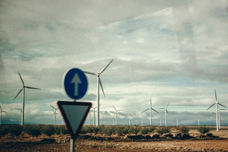 Scenic view of wind turbines and road sign in open countryside, emphasizing renewable energy.
