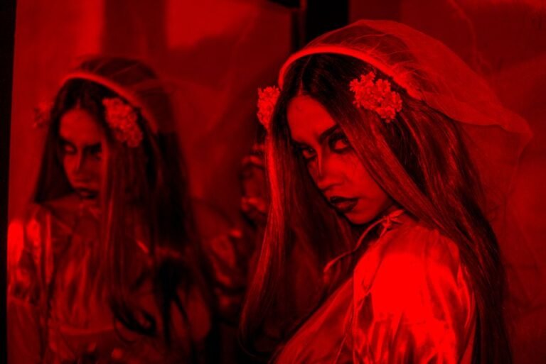 A haunting portrait of a woman with a gothic look in dramatic red lighting.