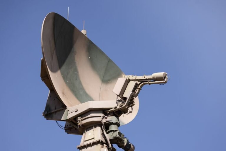 Close-up of a military radar system with a clear blue sky as background, showcasing advanced communication technology.