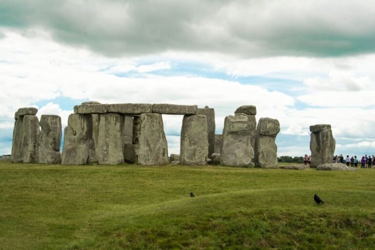 Stonehenge on a cloudy day with tourists in the distance, capturing its ancient allure.